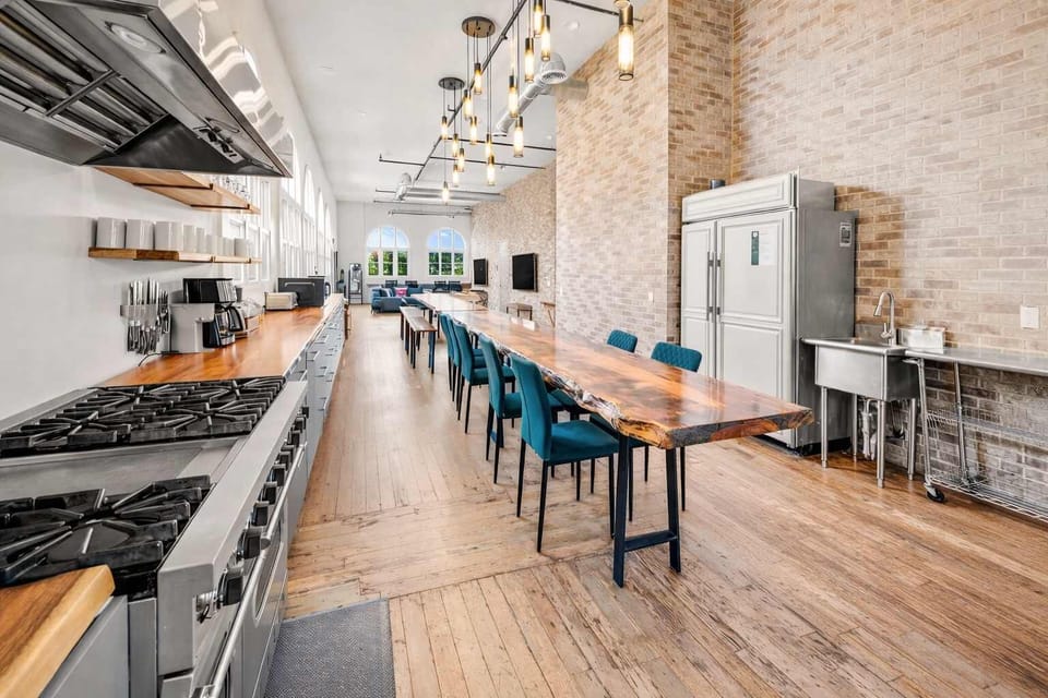 Open-Concept Kitchen with Long Dining Table, High-End Appliances, and Ample Seating — Ideal for Shared Meals, Entertaining, and Comfortable Gatherings