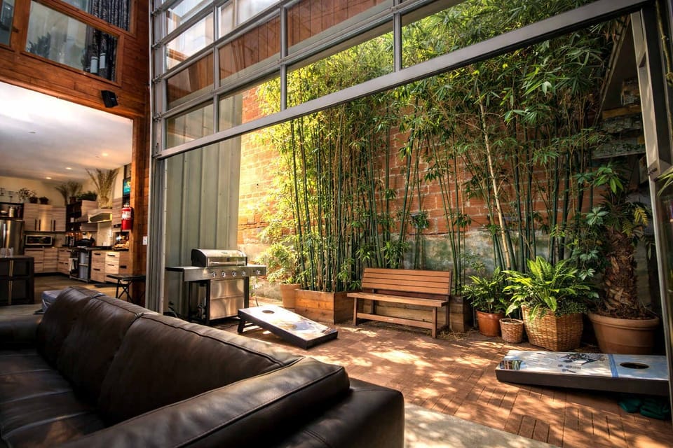 Indoor-Outdoor Bamboo Courtyard – Floor-to-Ceiling Glass Walls, Lush Tropical Greenery, and Relaxed Lounge Seating Blending Nature with Modern Comfort