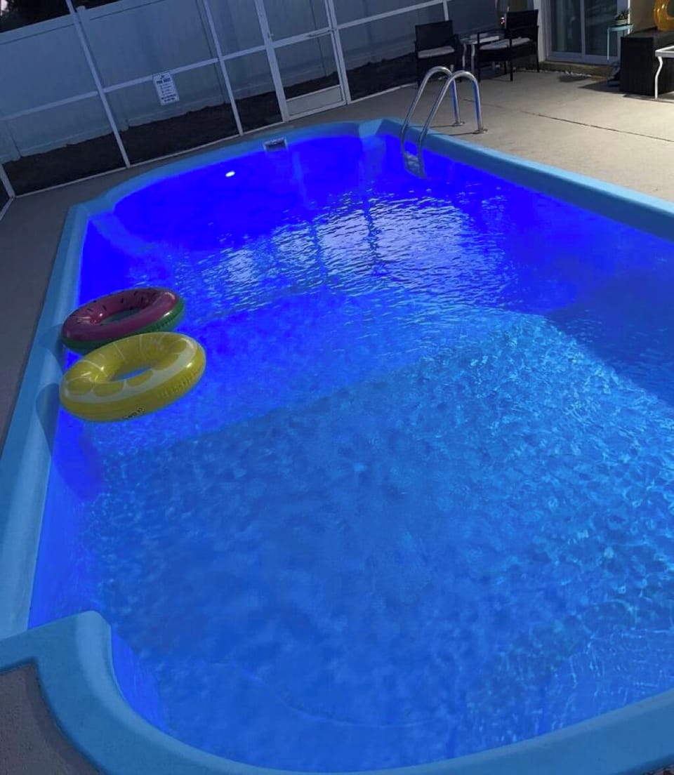 A softly lit nighttime pool reflects shimmering lights on its serene surface.