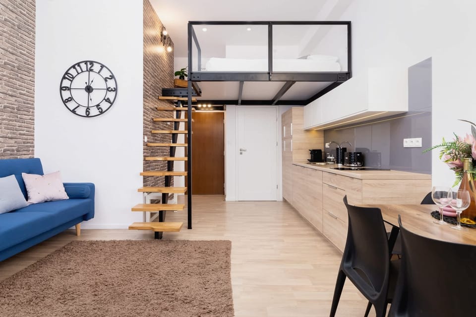 An open-concept living space with a comfortable sofa and built-in shelving. Floor-to-ceiling windows fill the area with natural light.