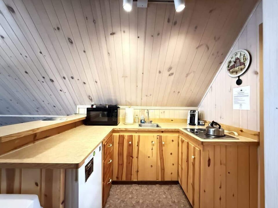 Kitchen equipped with mini fridge, basic cookware, dishes, and silverware.