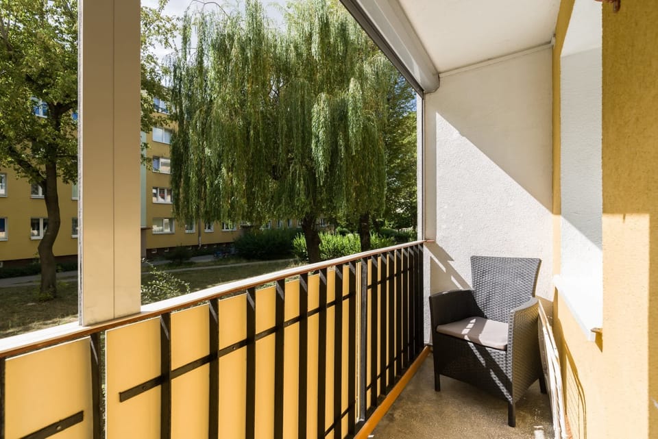 A balcony with outdoor furniture and views of a peaceful green courtyard.
