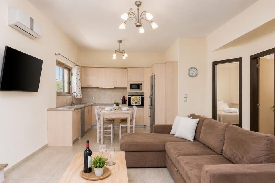 Open-plan living room with sofa, dining area, kitchen, ornamental fireplace, A/C, WiFi internet, and satellite TV