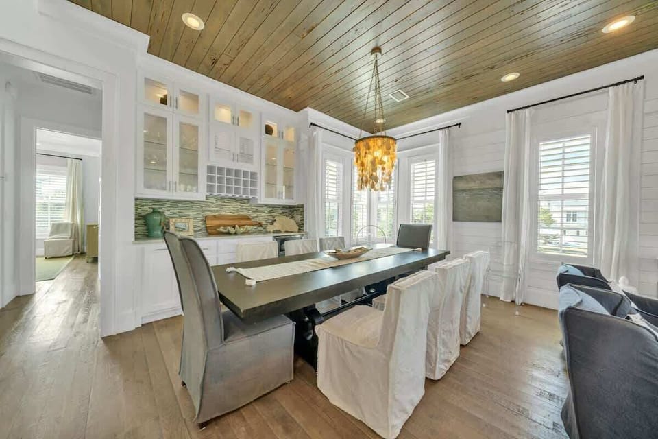 - Coastal chic dining room features a dramatic shell chandelier and rustic wood ceiling - Seating for eight ensures everyone gathers comfortably for meals or game nights - Glass cabinets and green tile backsplash add stylish functionality