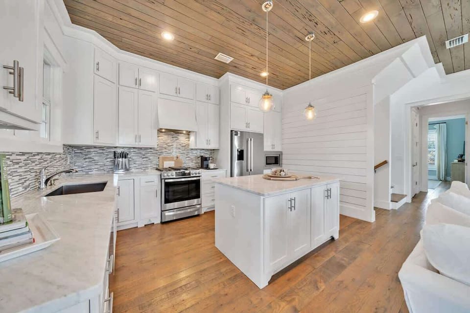 - Sleek white kitchen features stainless steel appliances and a spacious island for prepping meals or quick snacks - Beautiful backsplash and pendant lights add style and charm - Ideal for whipping up dinner or sipping morning coffee in peace