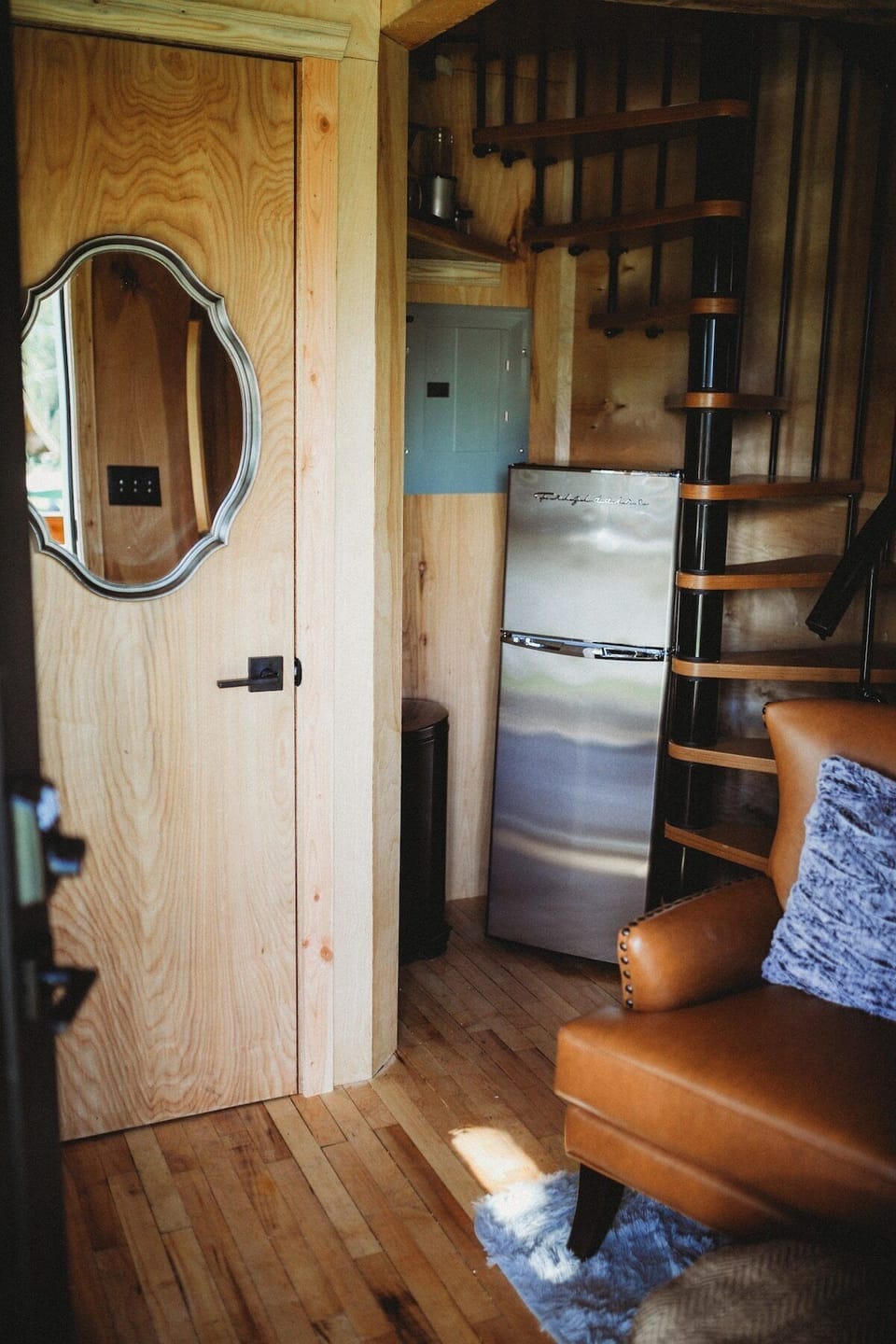 Cozy up in the treehouse living space with a modern touch—featuring a fridge, comfortable seating, and a spiral staircase.