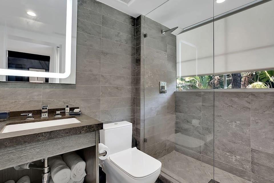 Refresh under a spacious rain shower in sleek stone tile.