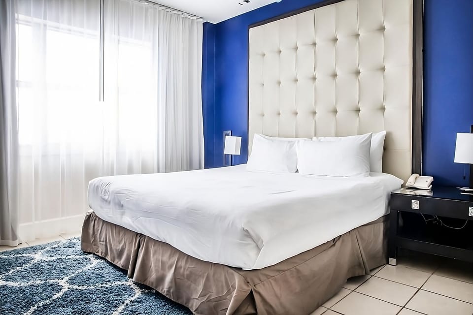 Sink into cloud-soft bedding beneath a dramatic tufted headboard.