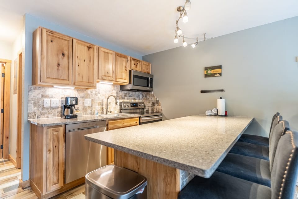 Full-sized kitchen with upgraded, stainless steel appliances and breakfast bar with seating for four.