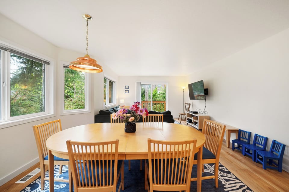 Gather around a spacious dining table where natural light and leafy views create a warm, inviting space for shared meals and memorable conversations with loved ones.
