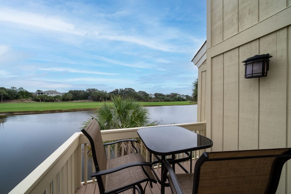 Primary bedroom deck features spectacular views of the pond and golf course with bistro table and chairs.
