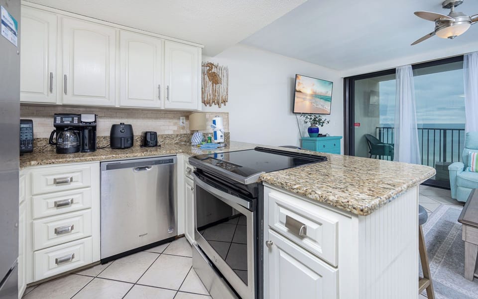 Kitchen with stainless appliances, coffee station, and a gorgeous view of the beach from the adjacent living area