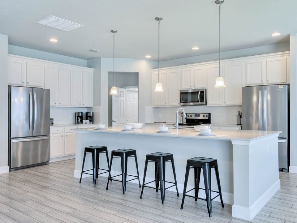 - Bright kitchen with island seating and modern design  
- Stainless steel appliances in family vacation rental  
- Spacious cooking area for group meals near Disney