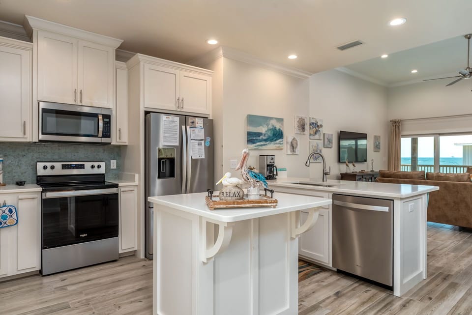Your fully equipped kitchen awaits with stainless steel appliances, granite counters, and coastal charm—perfect for preparing meals while ocean views beckon nearby.
