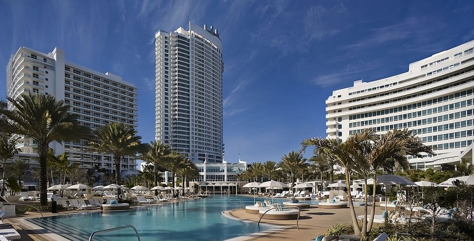 Dive into the sparkling resort pool surrounded by palms.