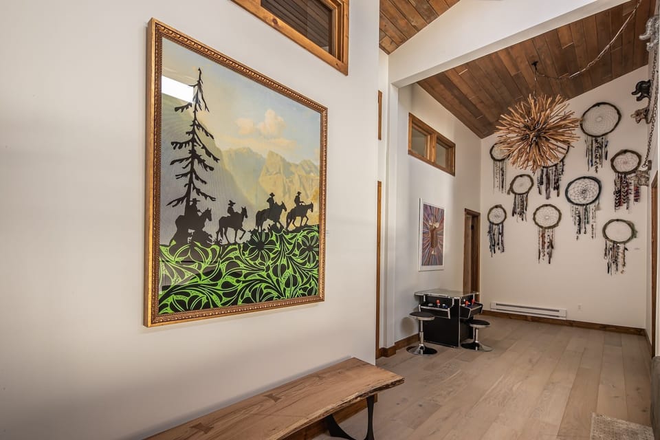 Step into your artistic retreat where mountain-themed artwork and handcrafted dreamcatchers create a cozy, inspiring atmosphere beneath soaring wooden ceilings.
