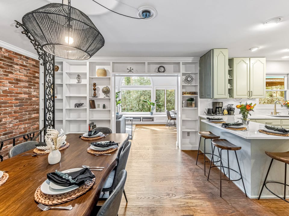 Semi-open layout with multiple dining spaces in dining room, kitchen, and sunroom
