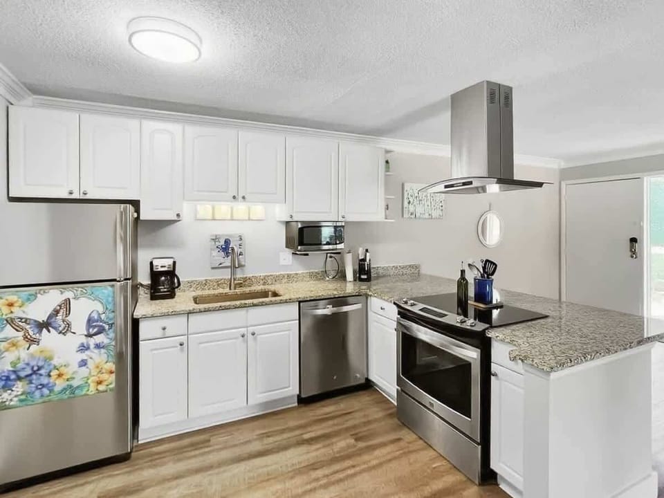A fully equipped kitchen with white cabinetry and stainless steel appliances.