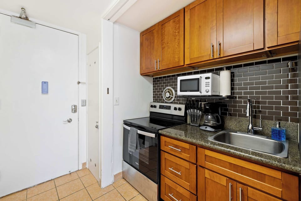 A cozy wooden kitchen featuring essential appliances and stocked wit some basics needed for cooking.