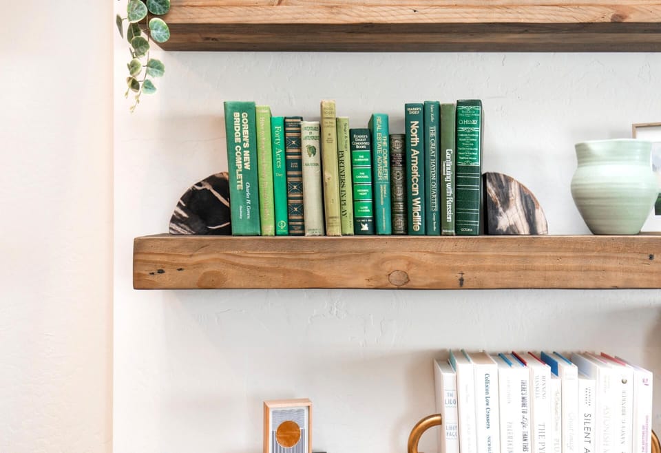 Green books line rustic shelf, adding charm and natural style.