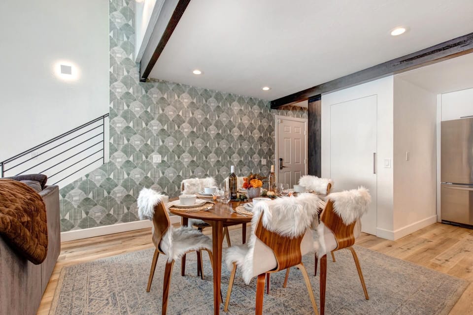 Stylish dining nook with furry chairs, geometric wallpaper, and warmth.
