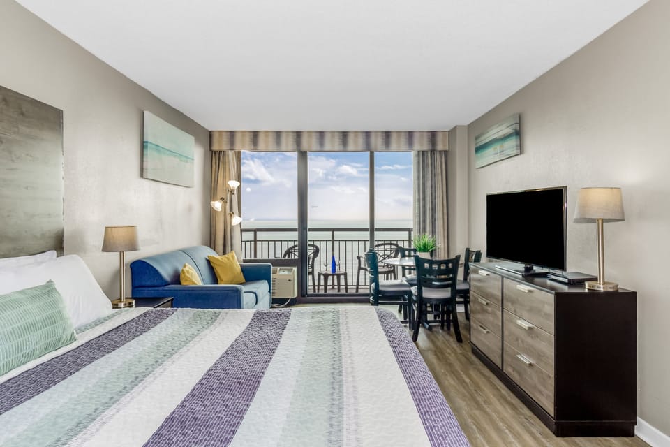 Lounge in seaside comfort in our studio suite, featuring a cozy bed and a stylish couch in the living area, creating an inviting space to unwind by the ocean.