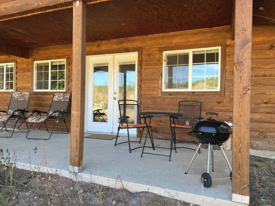 Front porch/patio equipped with charcoal grill and outdoor furniture for dining or relaxing. 