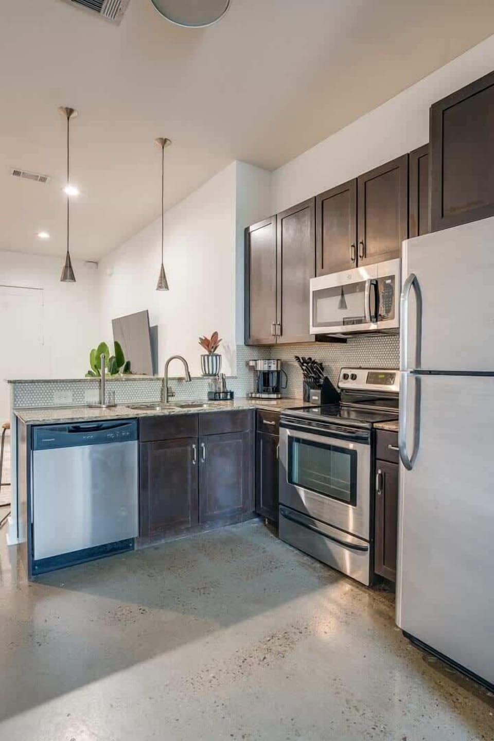Fully stocked kitchen with basic cooking essentials, stainless steel appliances, granite countertops, and breakfast bar seating.