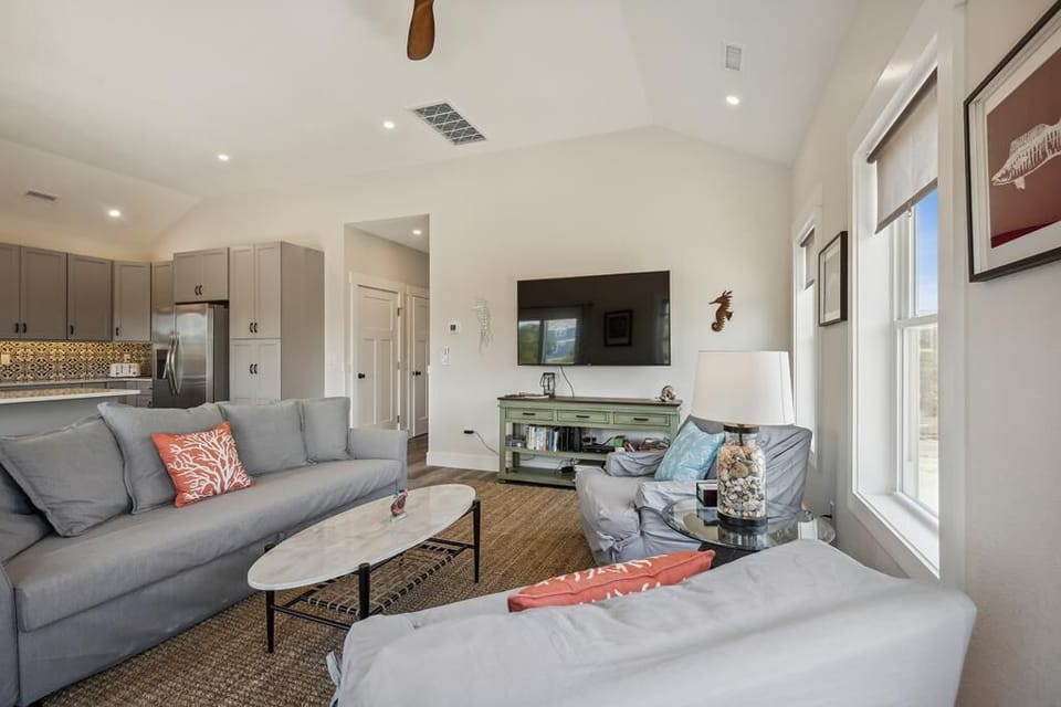 Relax in your spacious open-plan living room with vaulted ceilings, abundant natural light, and coastal-inspired décor—perfect for unwinding after a day of adventure.