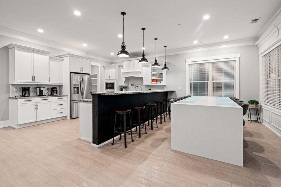 White cabinetry and a dark island with bar stools in the kitchen at Oceanside Charm in Cherry Grove