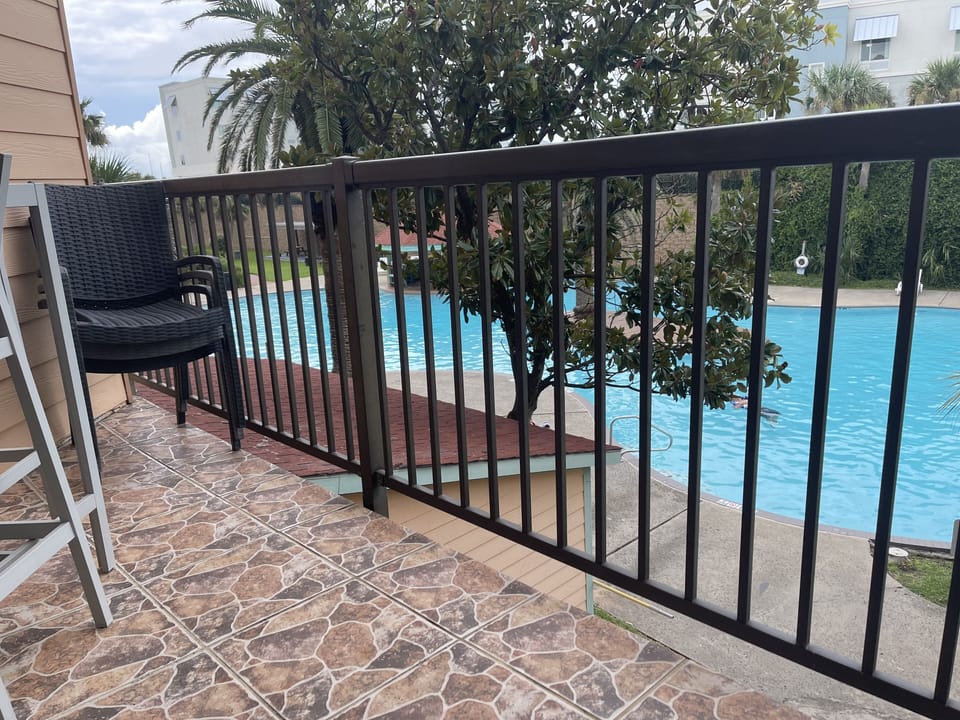 Balcony looking over resort size pool with table and chairs. 