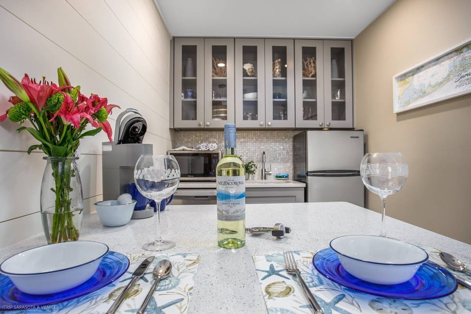 Modern kitchenette with a solid stone counter, seating for 2,  and basic food prep essentials (coffeemaker, blender, toaster, etc.)