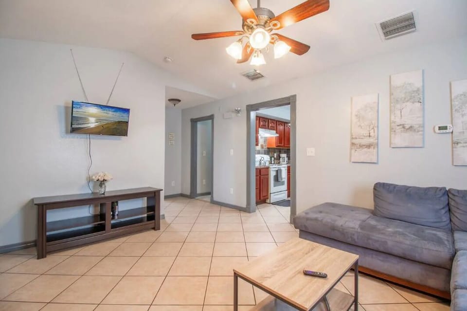 A bright living room with a comfortable sofa accompanied by a coffee table, tv and ceiling fancreates a cozy and warm atmosphere.