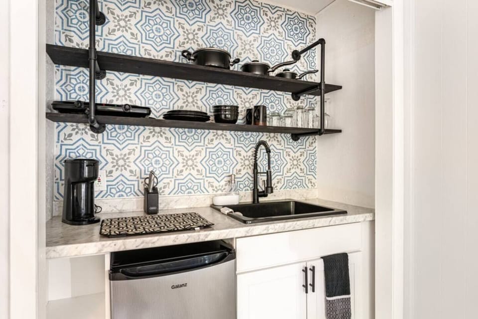 The bar in the room is compact and elegant, featuring a small countertop, sink, and mini-fridge