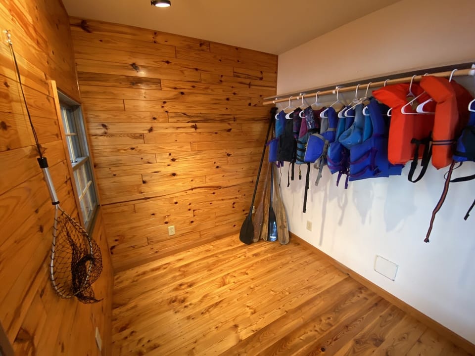 Boat house down by the water to store paddles, life jackets and fishing poles.