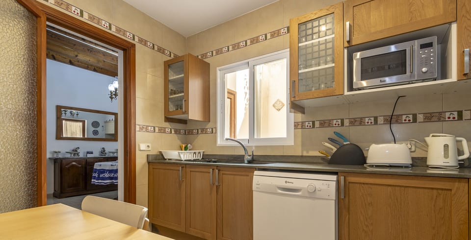 Spacious and fully equipped kitchen with wooden cabinets, modern appliances and a dining table.
