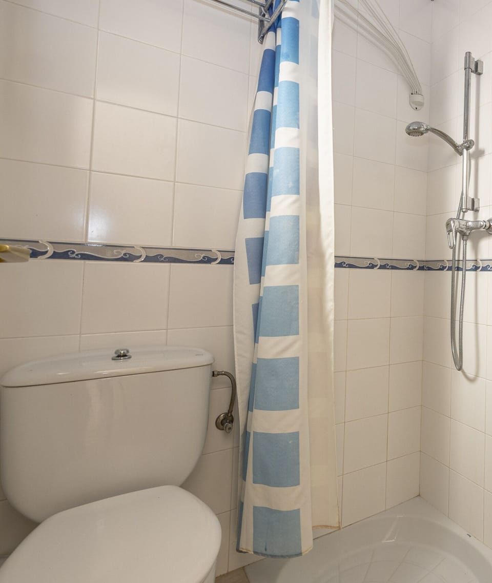 Full bathroom with shower, blue curtain and essential amenities, ideal for a comfortable stay.
