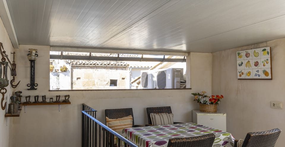 Covered outdoor dining area with table and chairs, perfect for enjoying meals in a bright and peaceful setting.