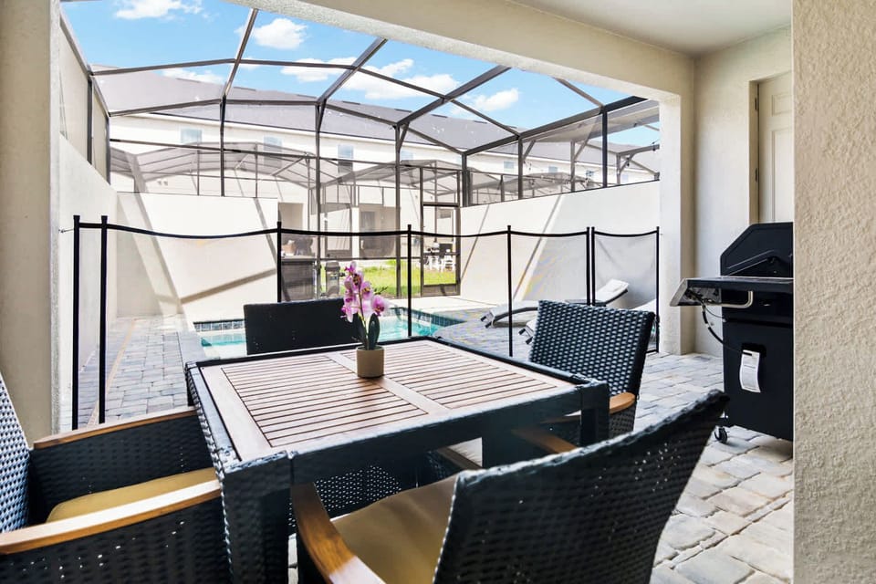Relax in your private screened patio with a poolside view and BBQ grill, perfect for family gatherings and outdoor dining.