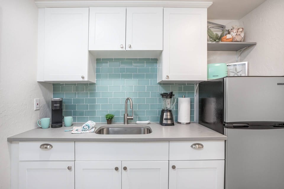 Updated kitchenette with glass tile backsplash, solid stone counter and stainless refrigerator.   Blender, toaster and microwave included.