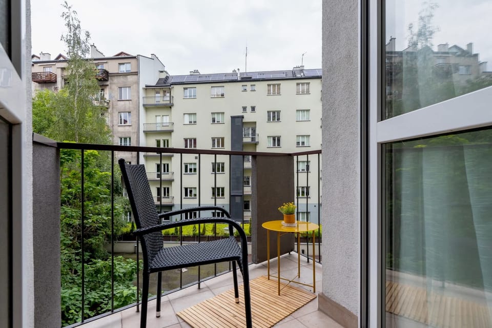 A closer view of the balcony with comfortable chairs and a small table, overlooking a peaceful residential area.
