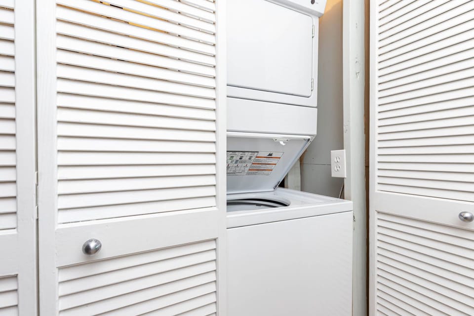 This laundry area features a convenient stacked washer and dryer behind stylish louvered doors for easy access