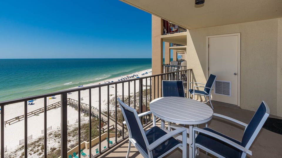 Bask in the refreshing beach view from this balcony, featuring a round table and comfortable seating for relaxation