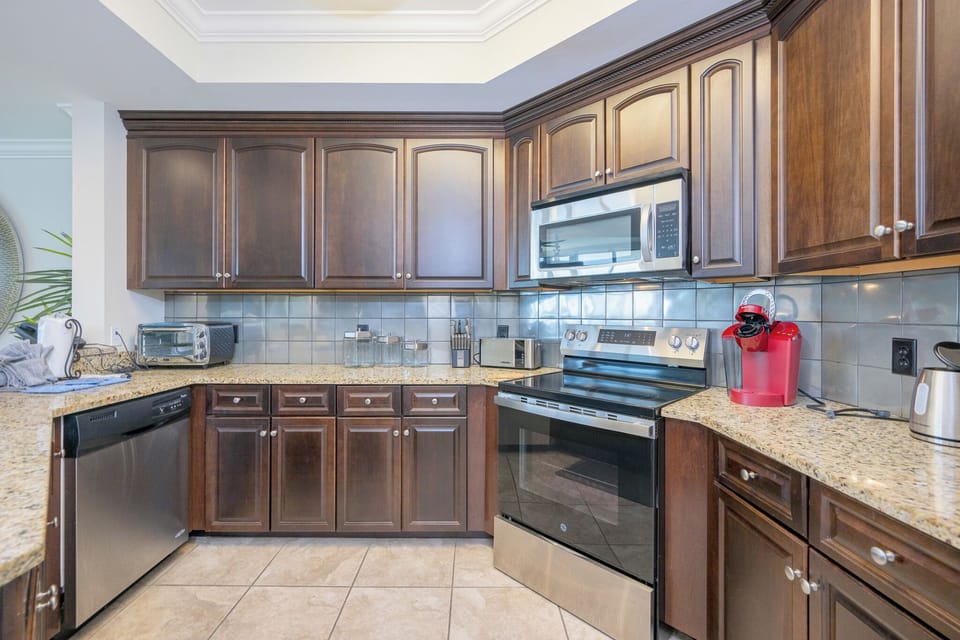 This kitchen features dark cabinetry, stainless appliances, and a granite countertop, perfect for preparing meals with a view