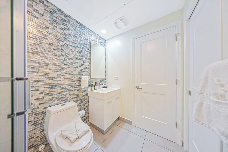 A bright bathroom with stylish mosaic tile and fresh towels awaits your arrival, offering a clean and welcoming space to refresh after your day of exploring.