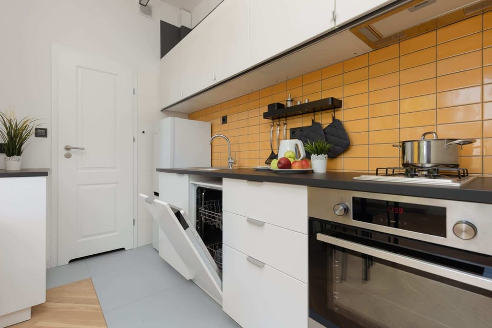 A view of the yellow and white kitchen with modern appliances and a cooking area.
