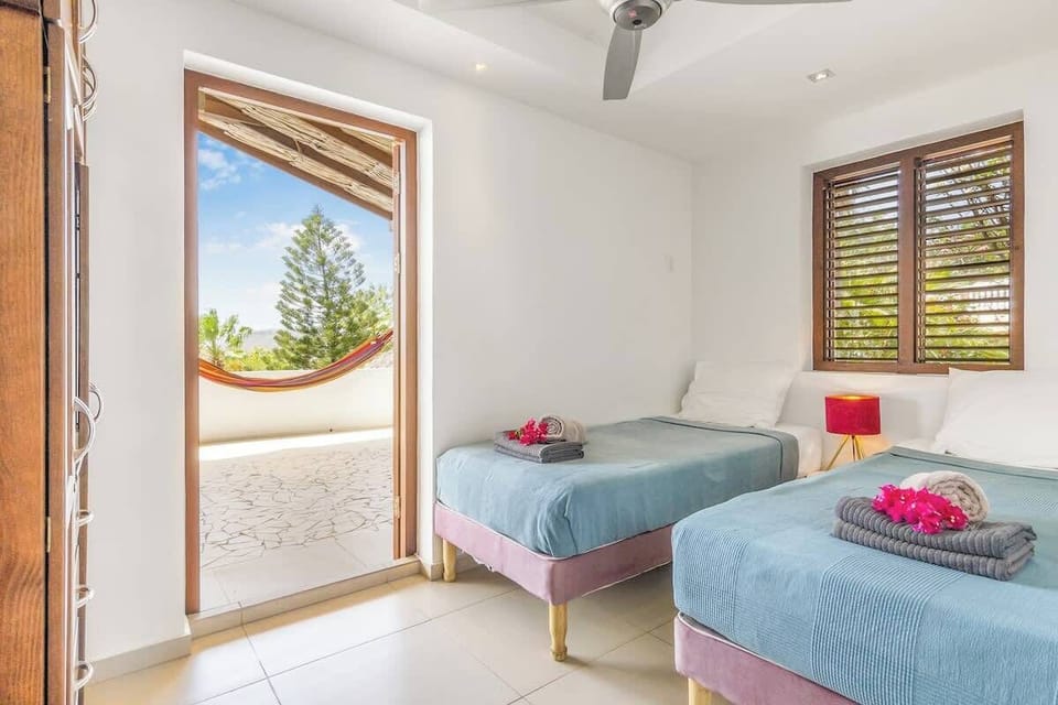 Bright twin bedroom with ceiling fan and terrace access. Step outside to your private hammock and enjoy the breeze — a charming space perfect for kids, friends, or relaxed mornings in the sun.
