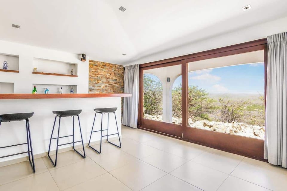 Chic indoor bar area with wide windows and ocean views — great for casual drinks or a quick breakfast before heading out.

