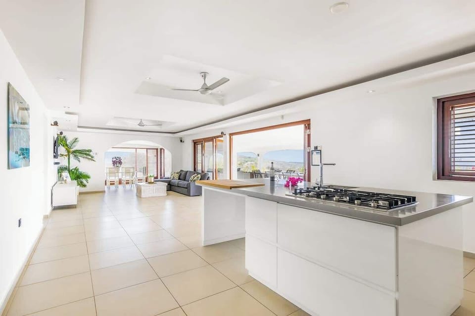Modern open kitchen with a large island, gas stove, and ocean views — fully equipped for cooking and gathering.