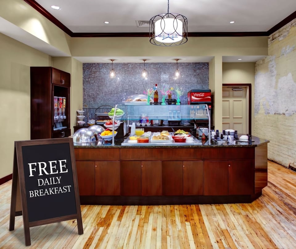Complimentary breakfast area featuring a kitchen-style layout with hardwood floors and pendant lighting.
